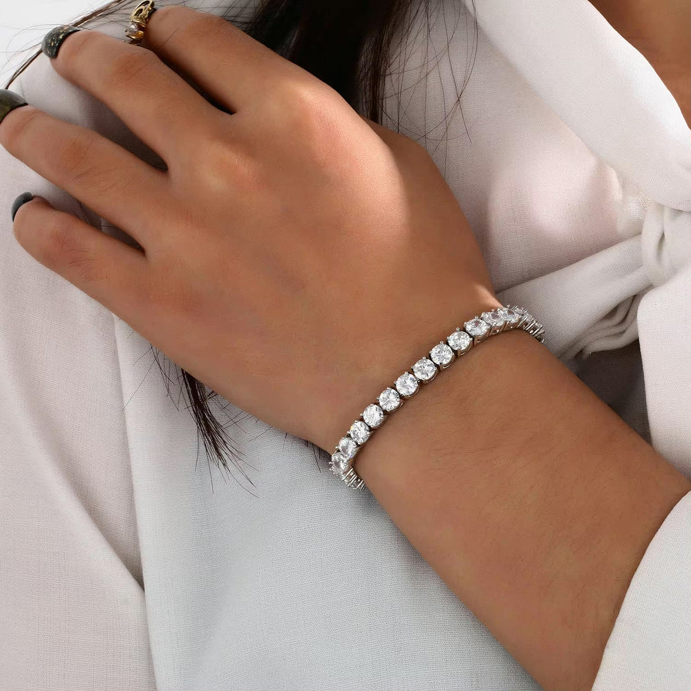 Close-up of a moissanite tennis bracelet on a woman's wrist with a white blouse